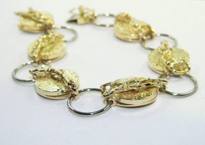 Goldenes Armband mit runden Anhängern und Kettengliedern in einem neutralen Design.